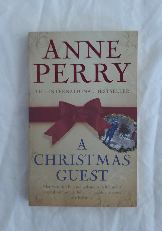 Book cover of 'A Christmas Guest' by Anne Perry, featuring a beige background with a large dark red ribbon bow across the center and blue title text.