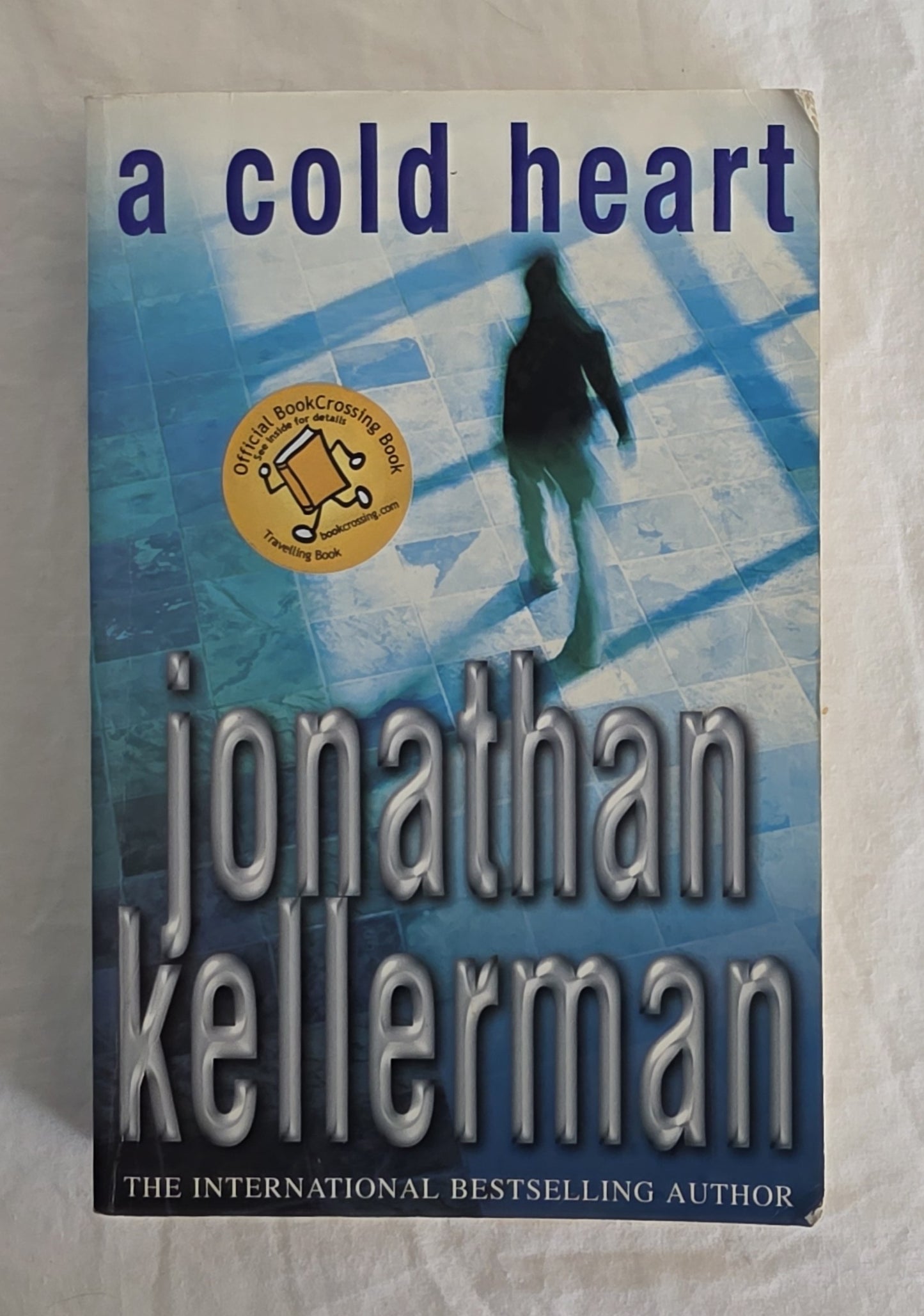 Book cover of 'A Cold Heart' by Jonathan Kellerman with a silhouette on a blue background.