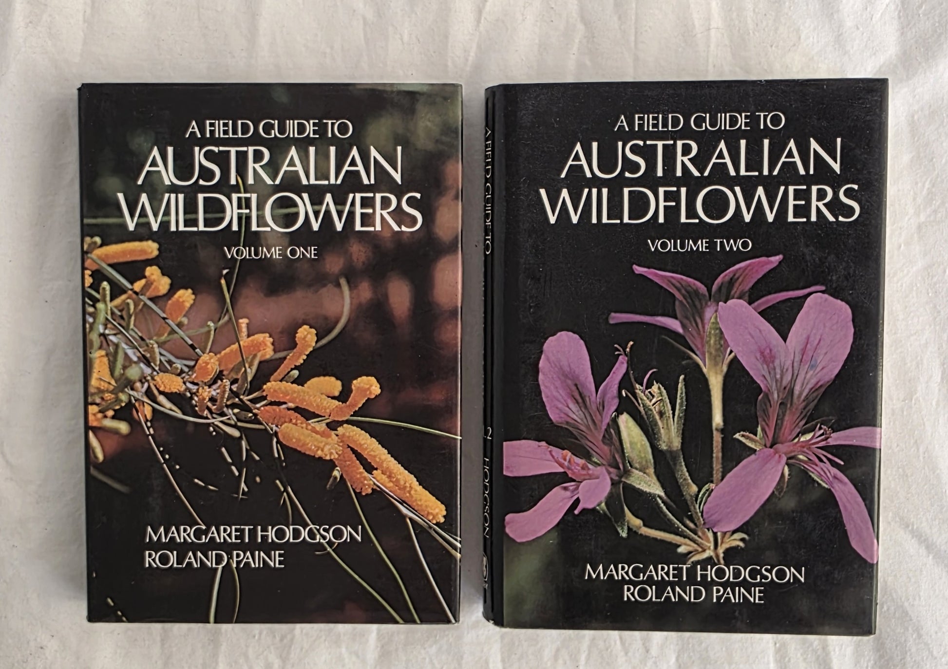 Two books titled 'A Field Guide to Australian Wildflowers' by Margaret Hodgson and Roland Paine on a textured surface.
