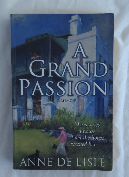 A hardcover book titled 'A Grand Passion: A Memoir' by Anne de Lisle, featuring a dark blue and white painted house illustration on the cover, photographed against a white fabric background.