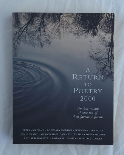 A book titled 'A Return to Poetry 2000' lying flat on a light fabric surface. The cover features a dark, moody photograph of tree branches reflected in still water, with white and light gray text on the right side and a list of poets at the bottom.