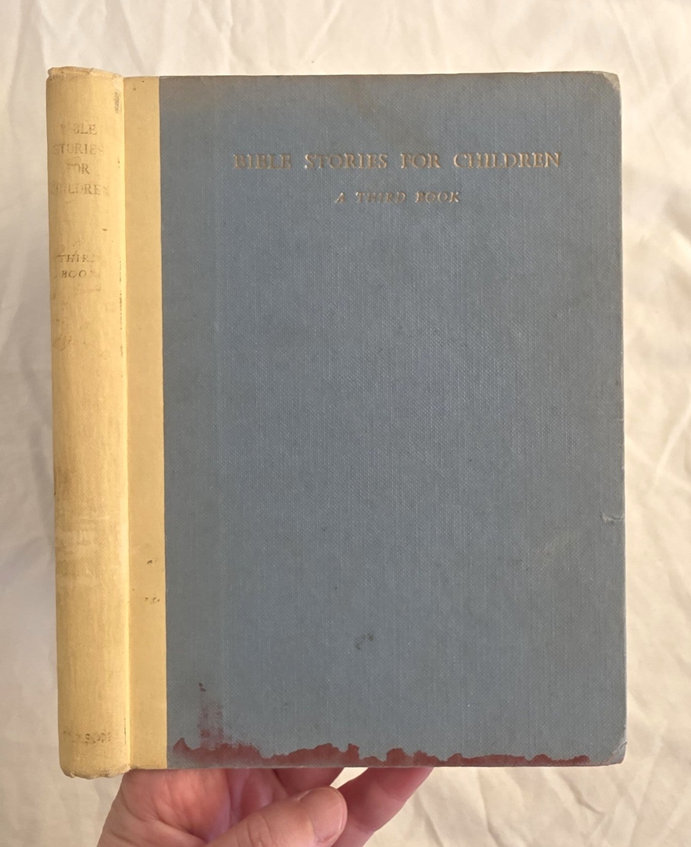 Vintage book titled 'Bible Stories for Children' held by a hand on a light background