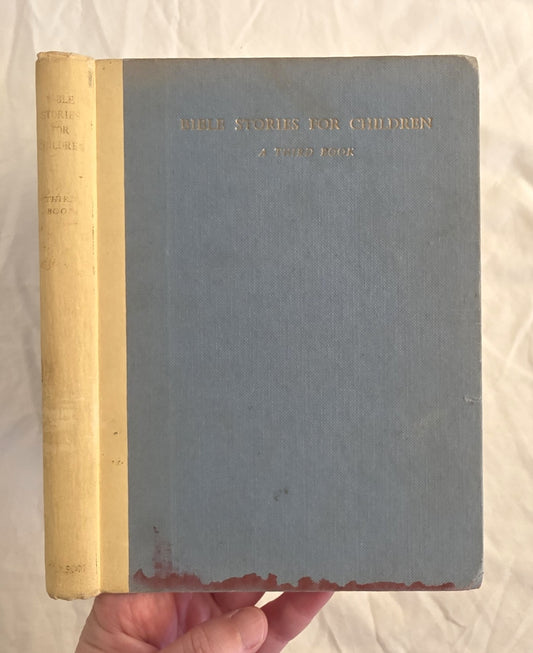Vintage book titled 'Bible Stories for Children' held by a hand on a light background