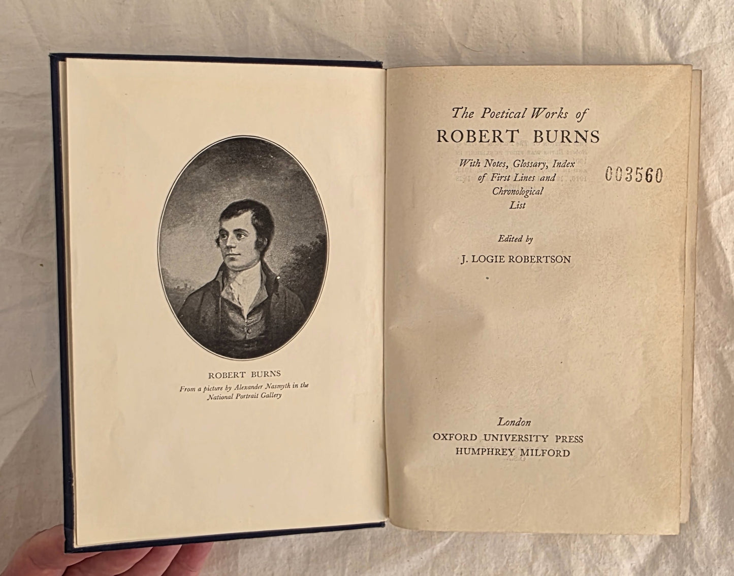 Open book showing the title page and portrait of Robert Burns on a textured beige background