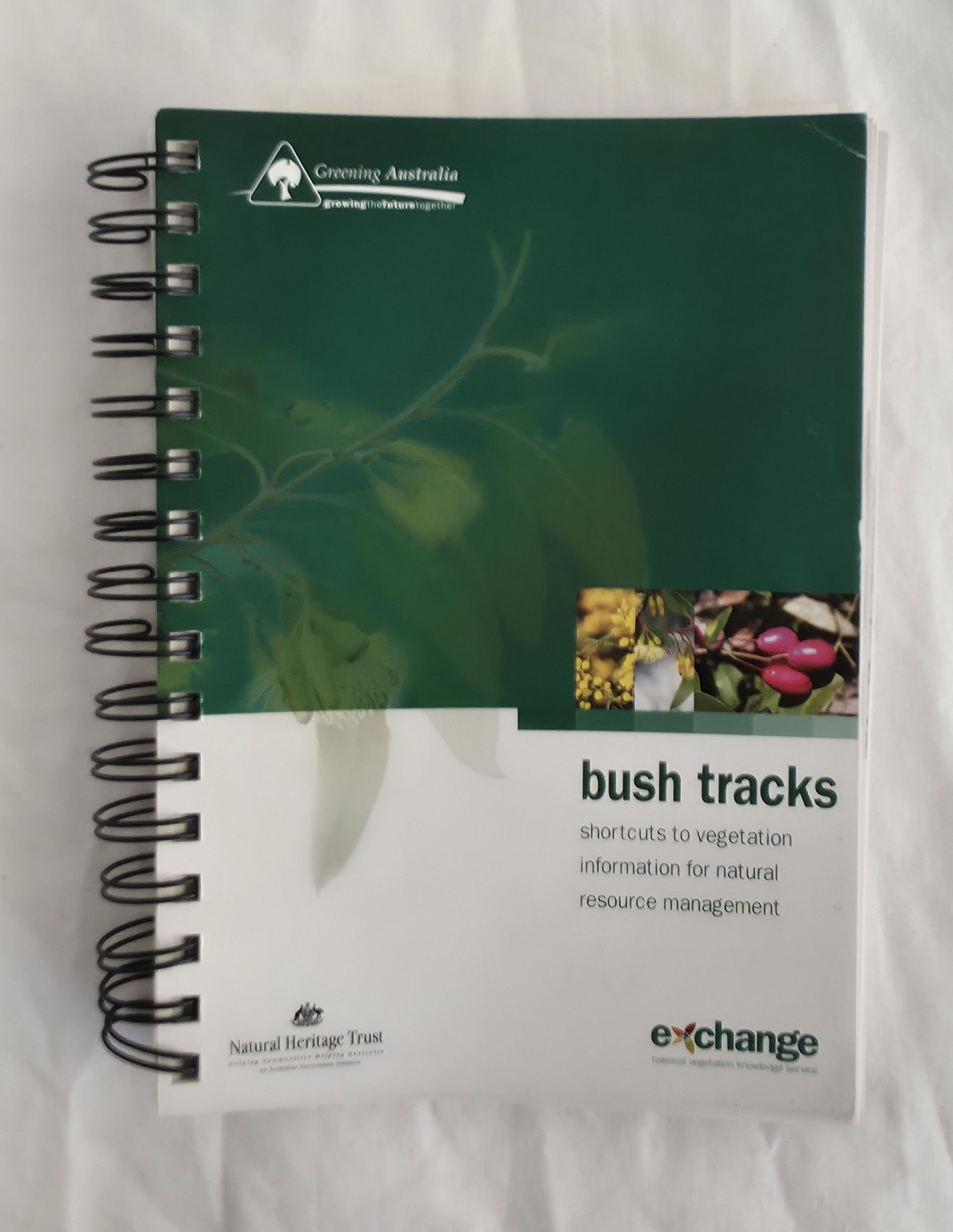 Spiral-bound book titled 'bush tracks' with green cover and white text section on a white background