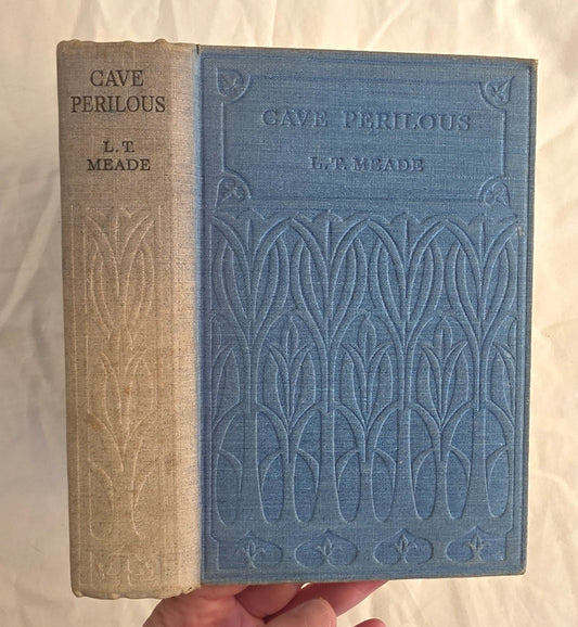 Book titled 'Cave Perilous' by L.T. Meade with embossed design on a white background