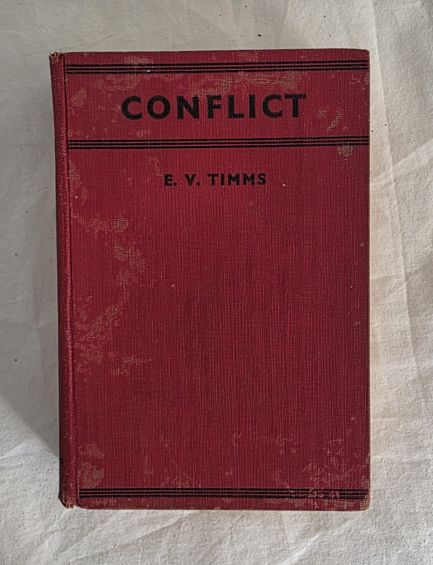 Red book titled 'Conflict' by E.V. Timms on a textured white background