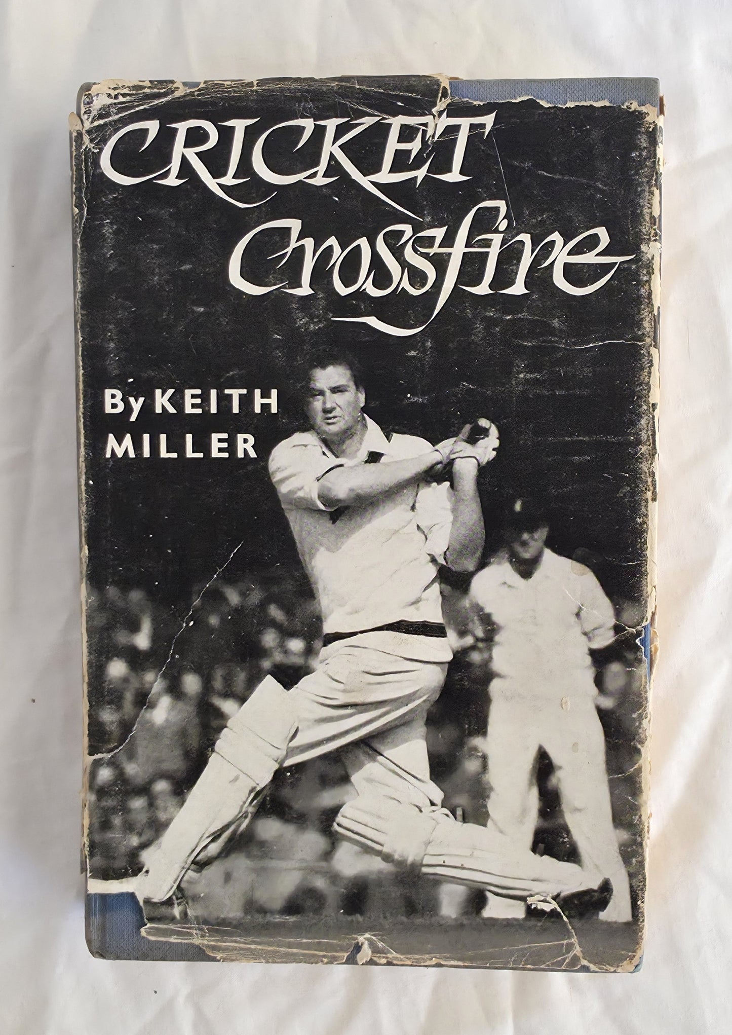 Book cover of 'Cricket Crossfire' by Keith Miller with a black and white photograph of a cricket player on a white background.