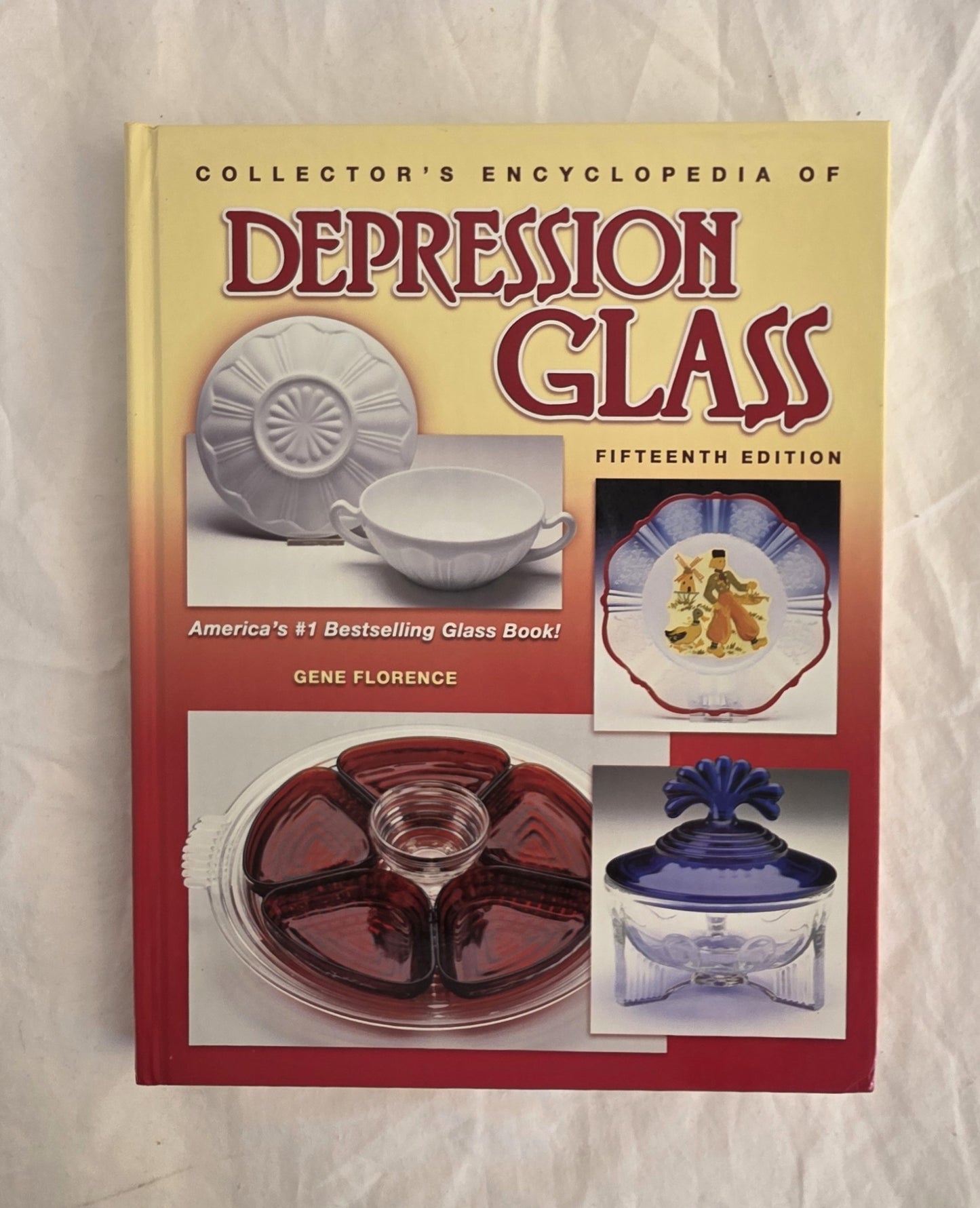 Book titled 'Collector's Encyclopedia of Depression Glass' on a textured beige background
