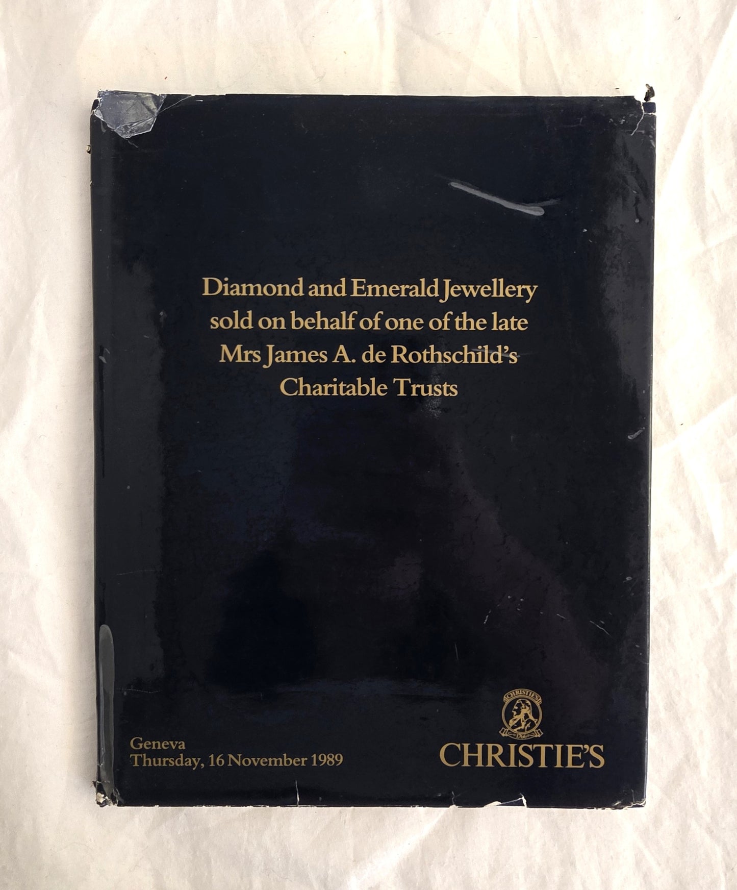 Black book with gold text about Christie's diamond and emerald jewelry sale, on a white background.