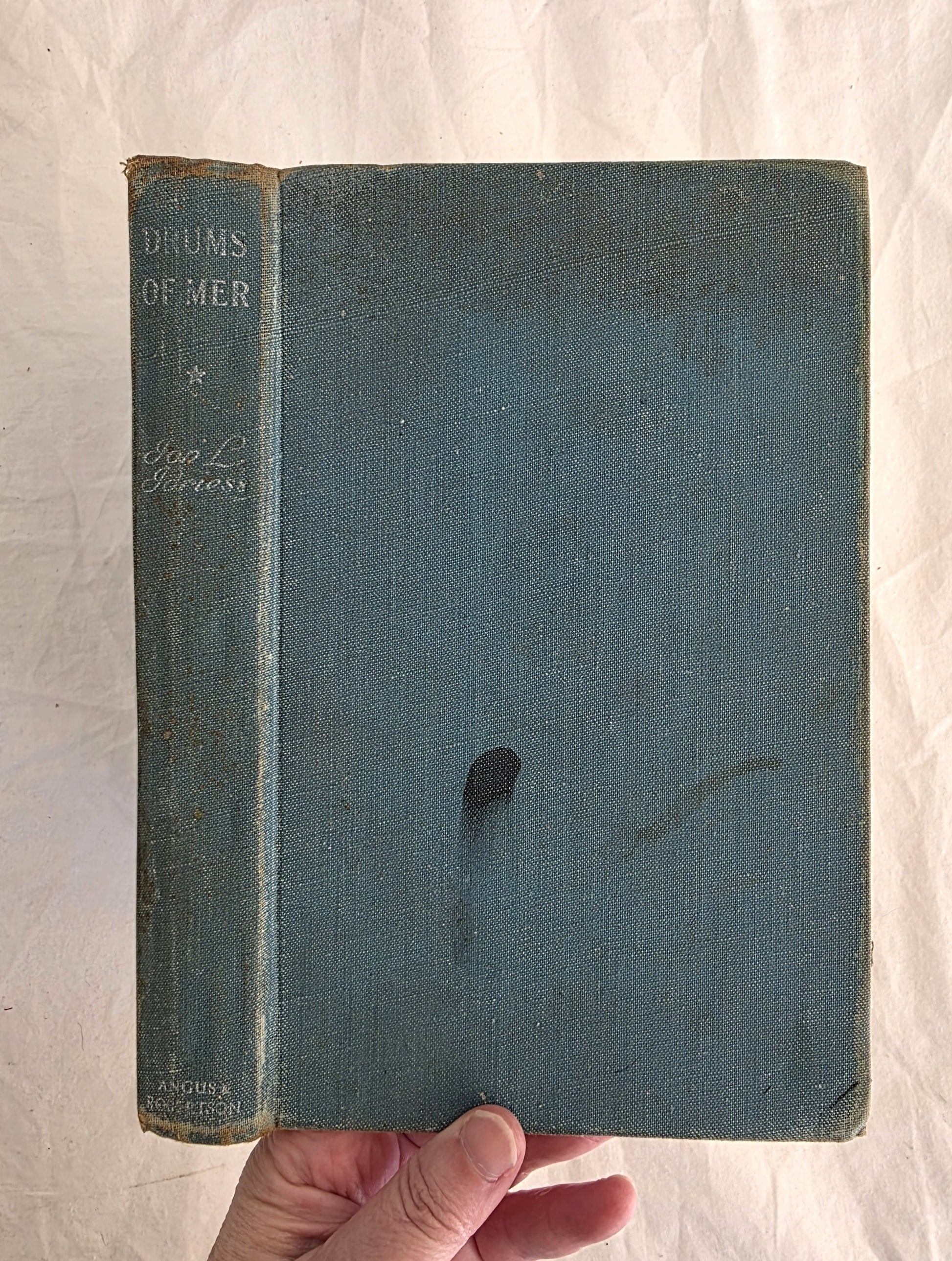 Vintage book with a blue cover held by a hand on a white background