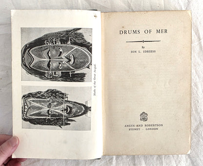 Open book titled 'Drums of Mer' by Ion L. Idriess with illustrations on a white background