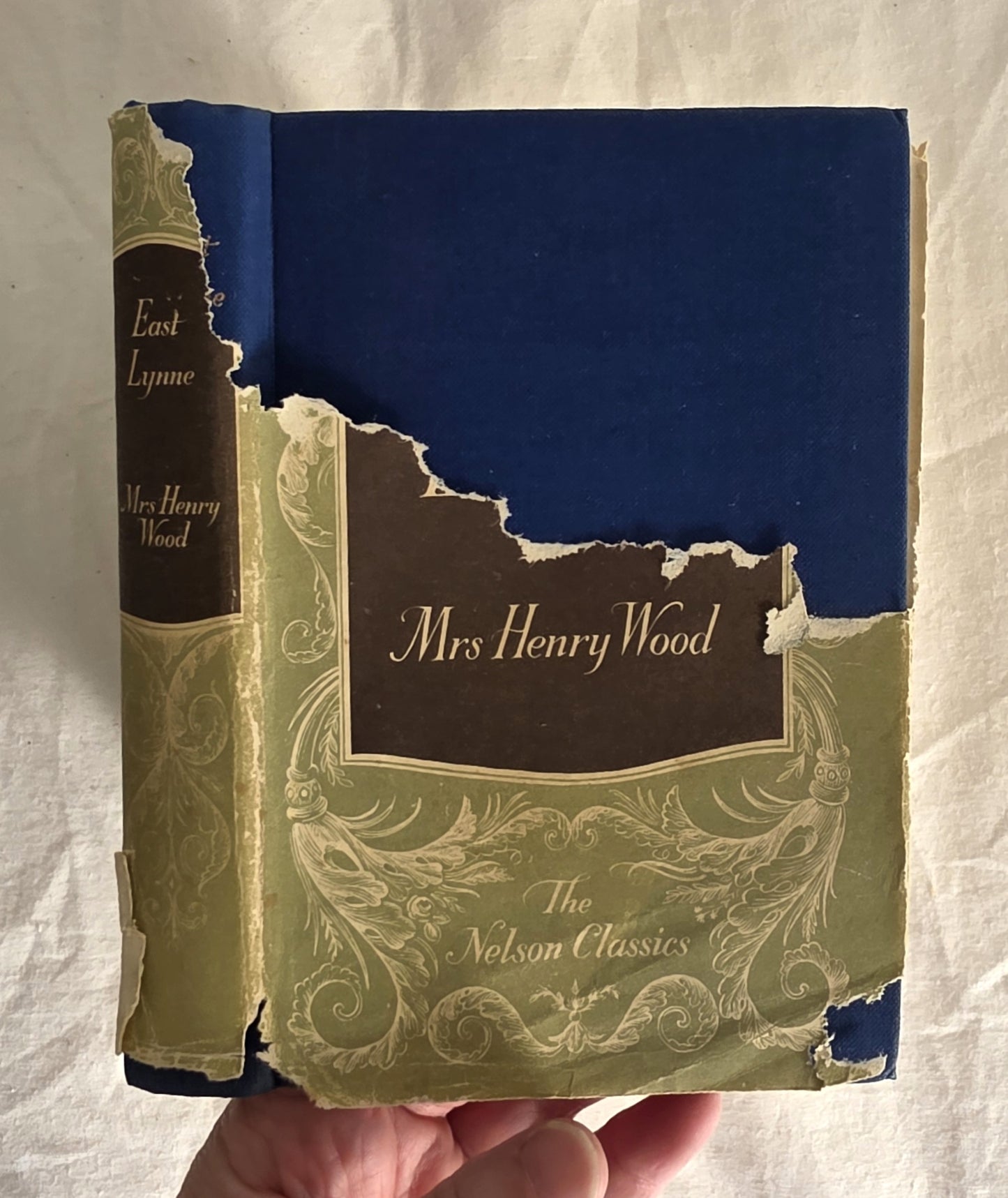 Vintage book titled 'East Lynne' by Mrs. Henry Wood with a torn spine on a white background