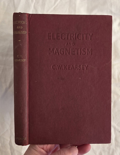Maroon book titled 'Electricity and Magnetism' by C.W. Kearsey held against a light background