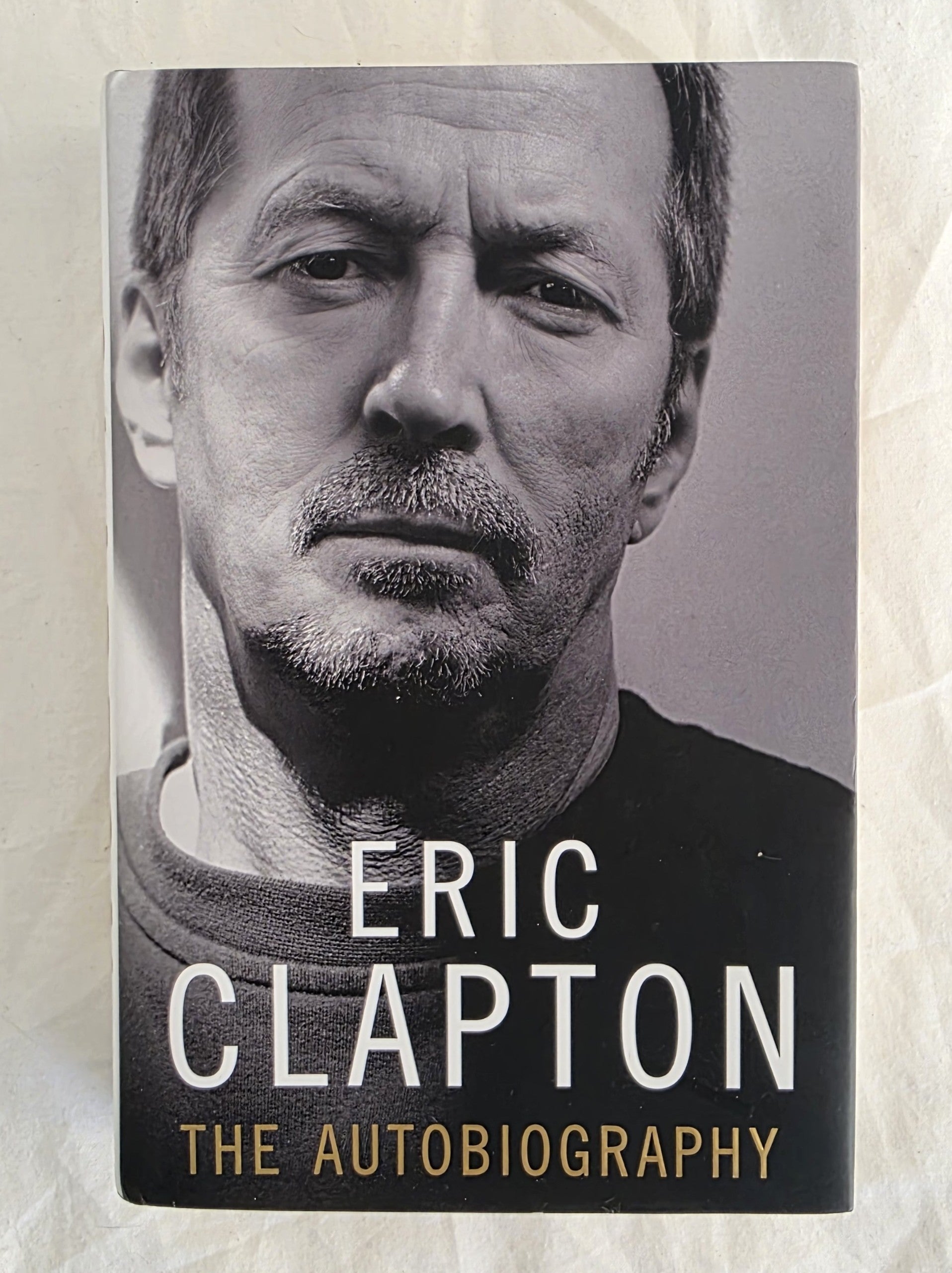 Book cover of 'The Autobiography' by Eric Clapton with a black and white portrait on a textured beige background.