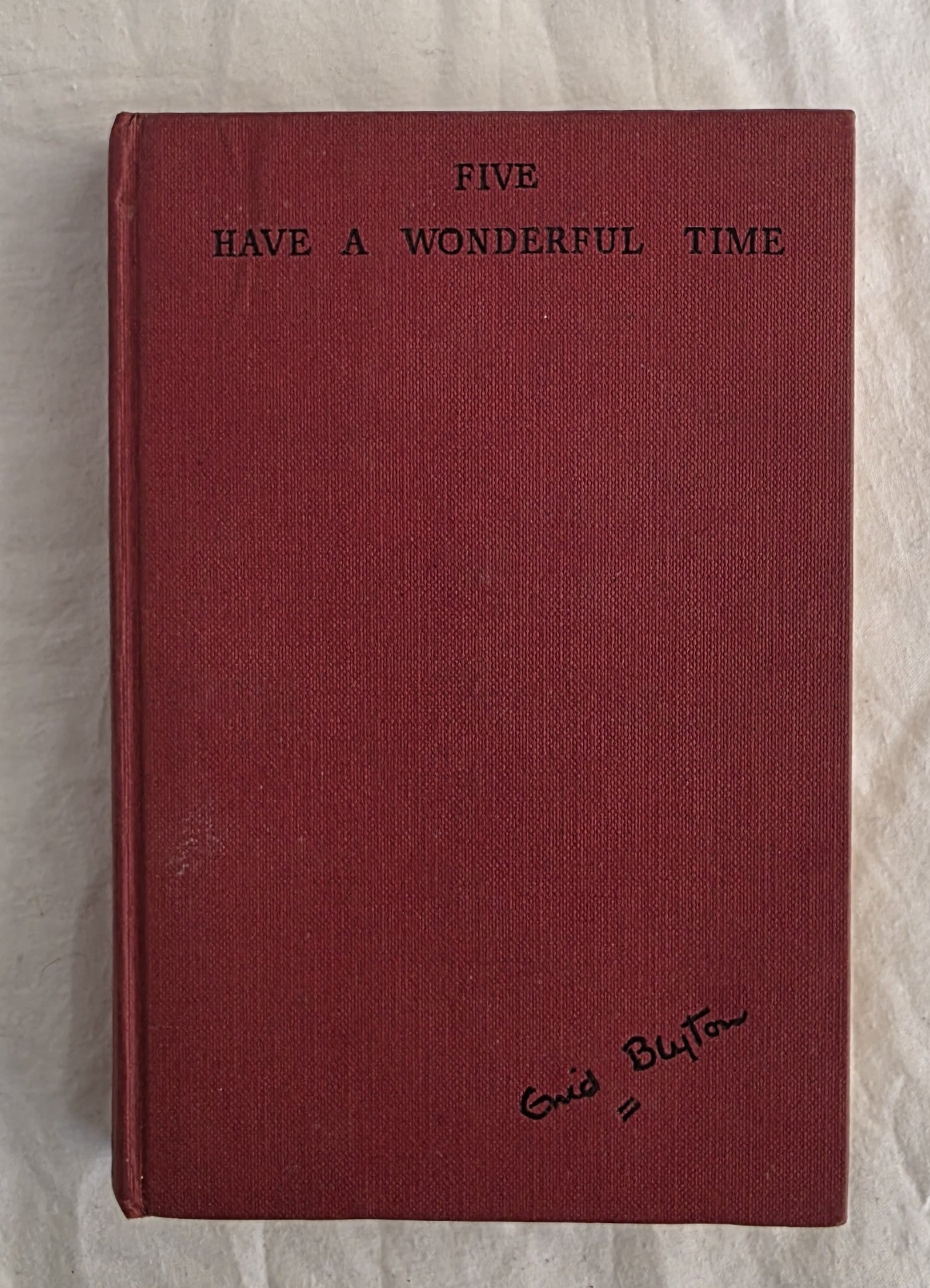 Red book with text 'Five Have a Wonderful Time' and signature on a textured surface