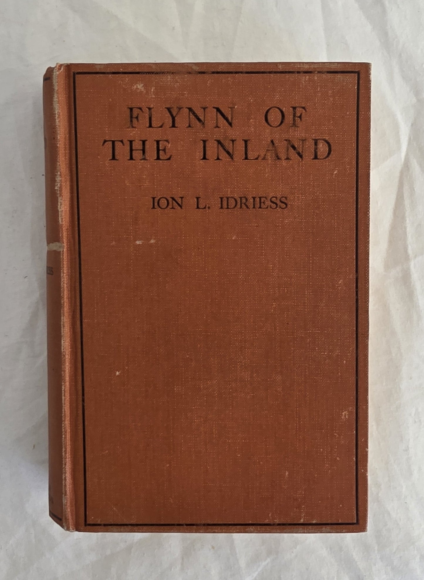 Vintage book titled 'Flynn of the Inland' by Ion L. Idriess on a textured white background