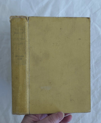 Yellowed book cover held by a hand on a white background