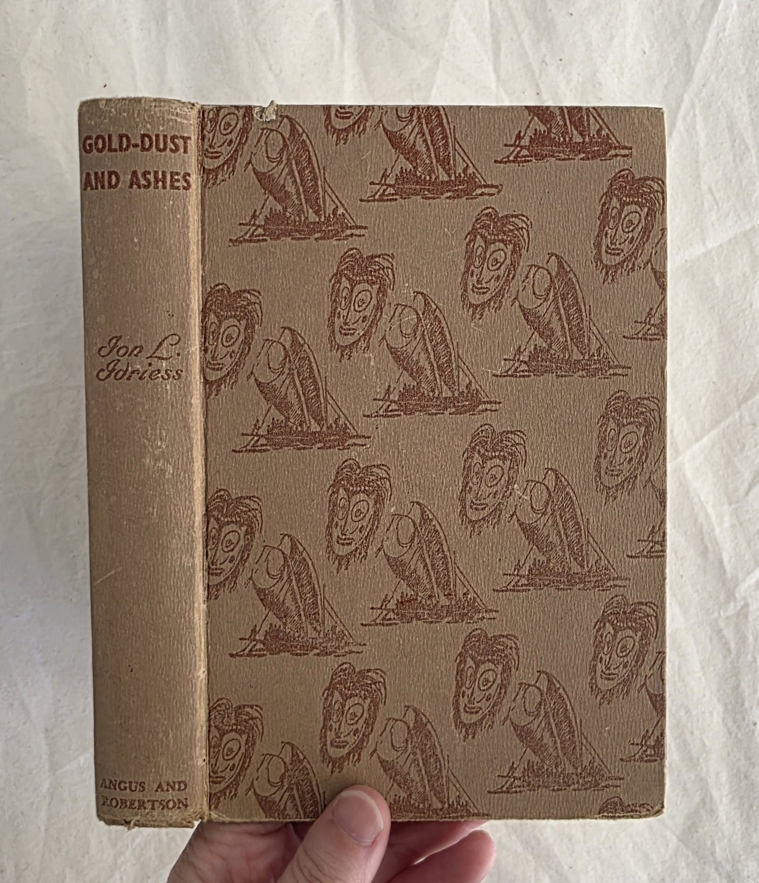 Vintage book with decorative cover held by a hand on a textured white background