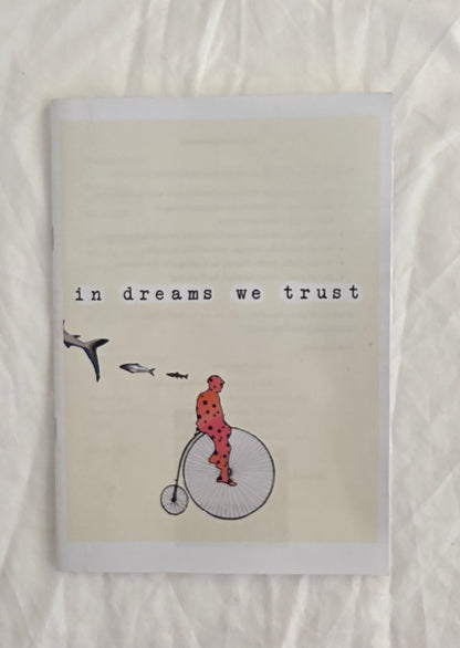 Notebook with illustration of a person on a penny farthing bicycle and text 'in dreams we trust' on a textured beige background.