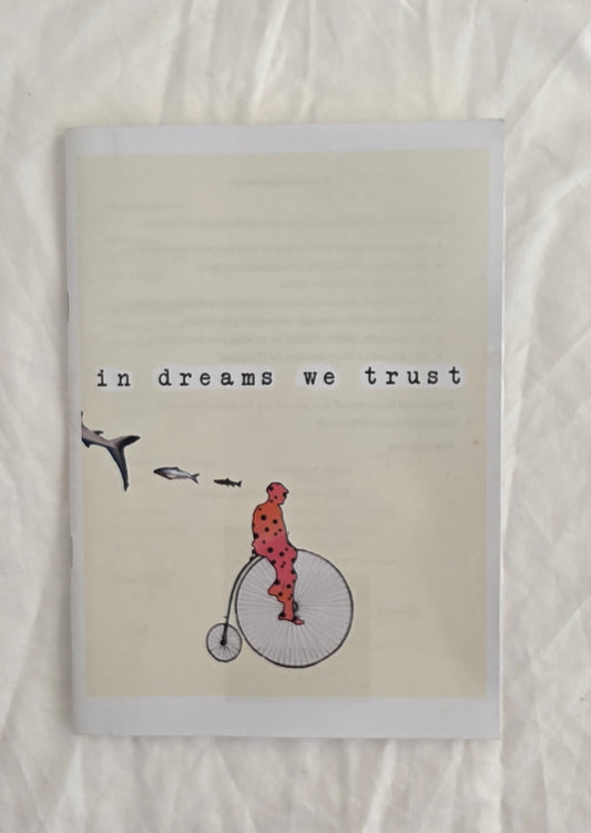 Notebook with illustration of a person on a penny farthing bicycle and text 'in dreams we trust' on a textured beige background.