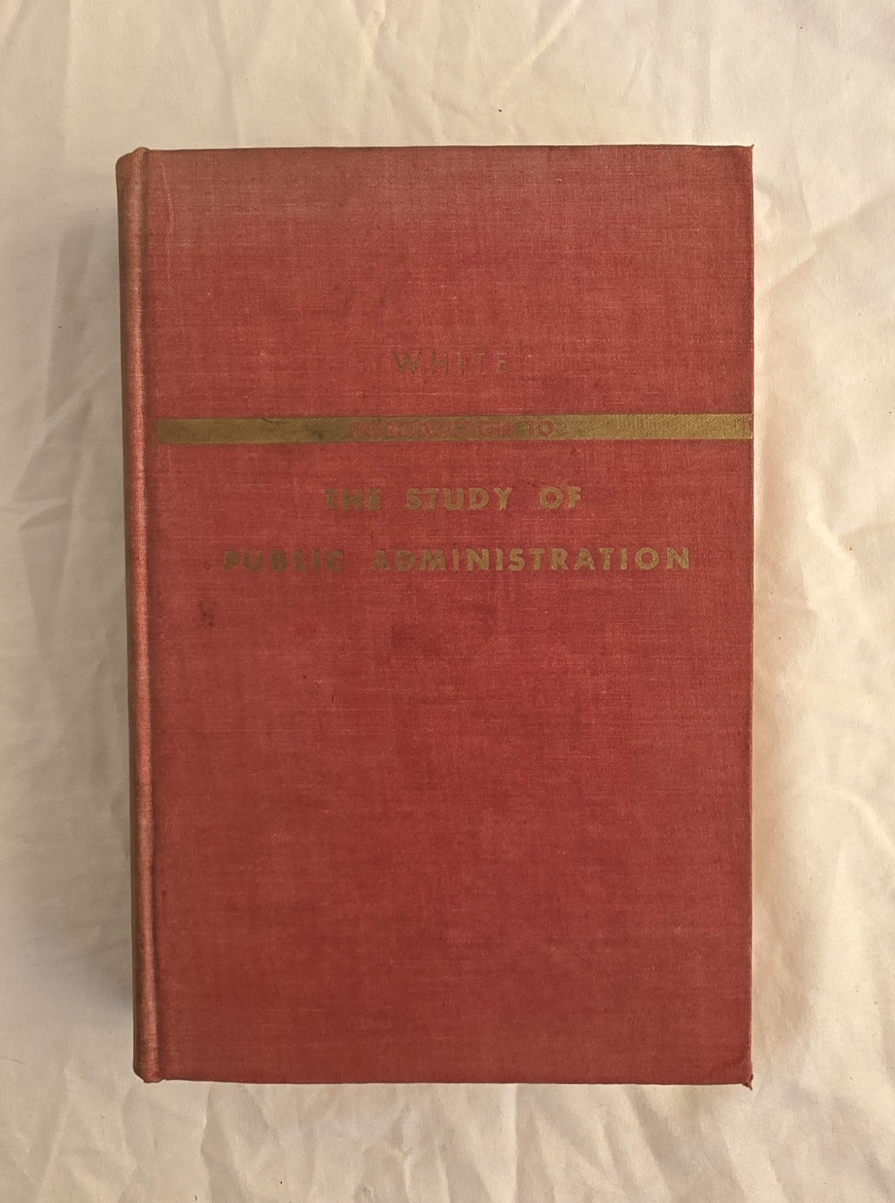 Red book with gold band and text on a beige background