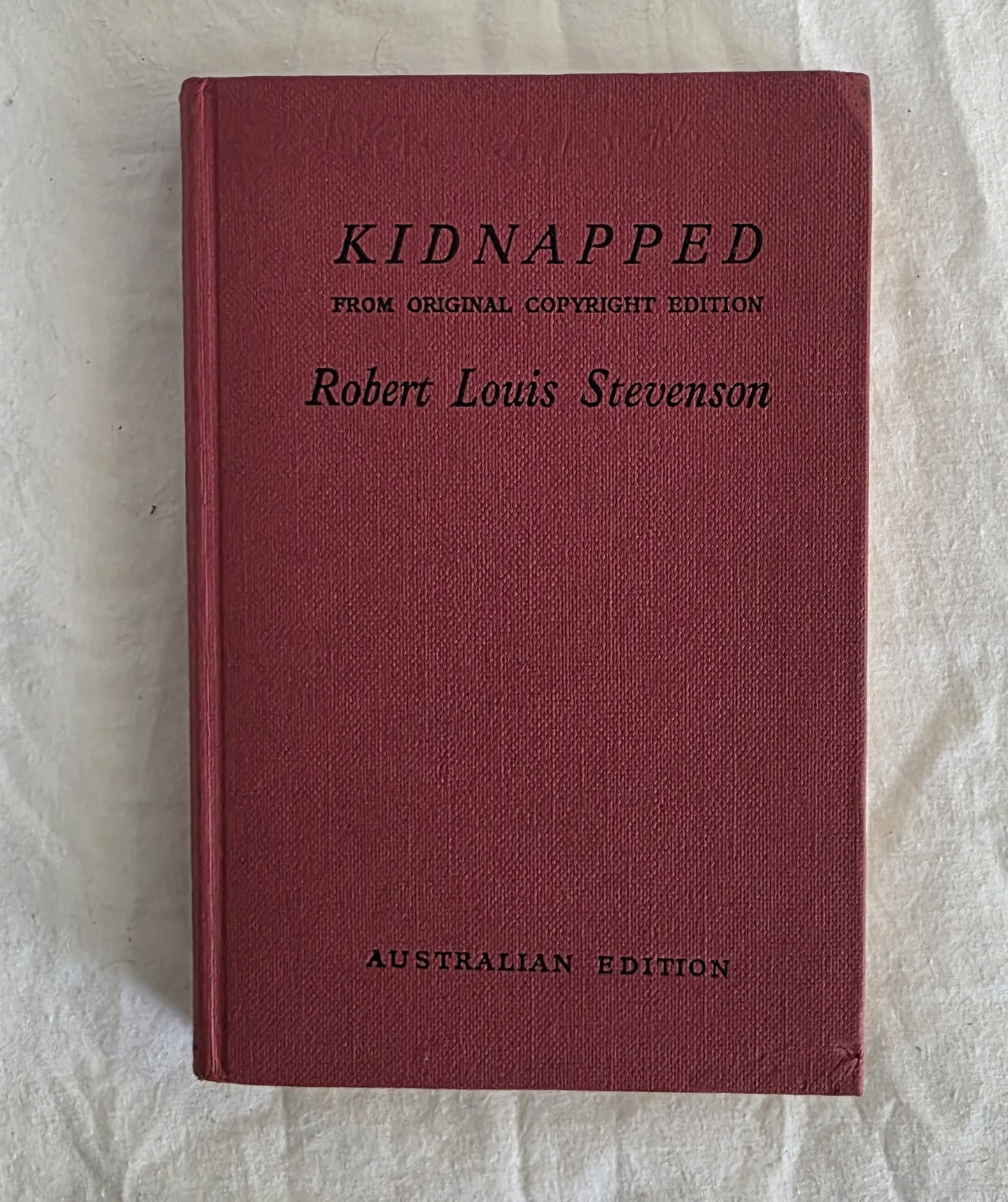 Red book titled 'Kidnapped' by Robert Louis Stevenson on a light background