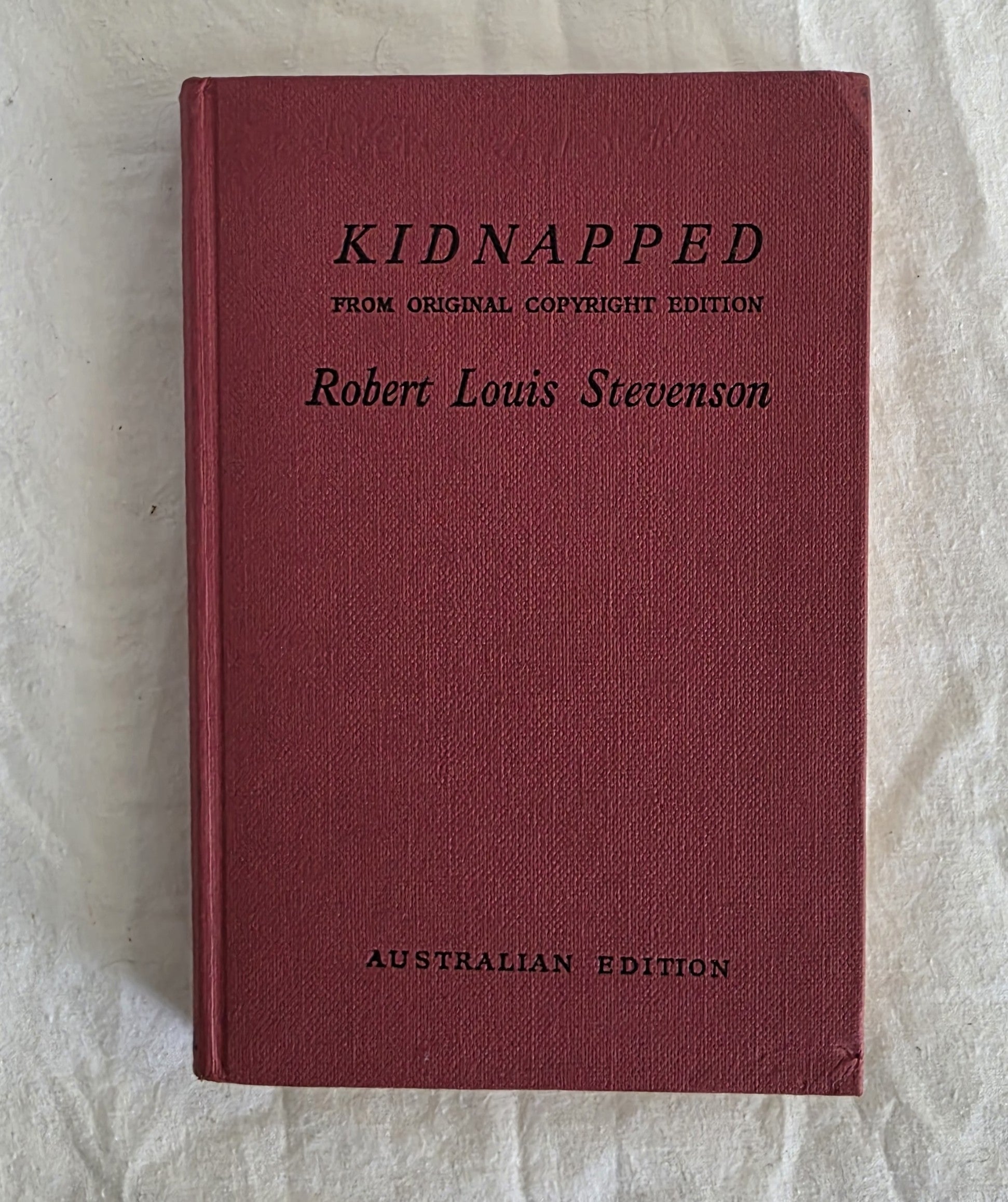 Red book titled 'Kidnapped' by Robert Louis Stevenson on a light background