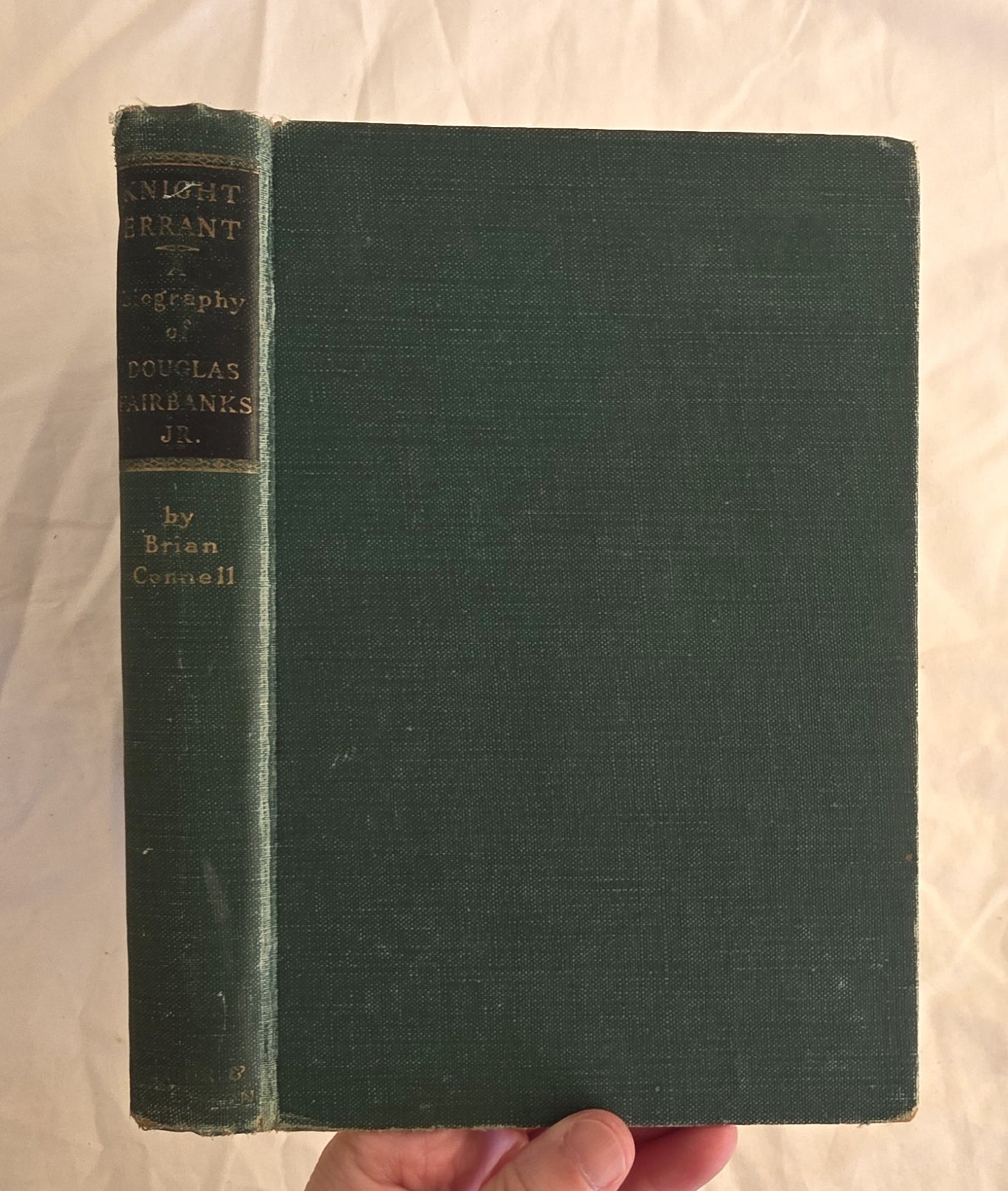 Green book held by a hand on a white background