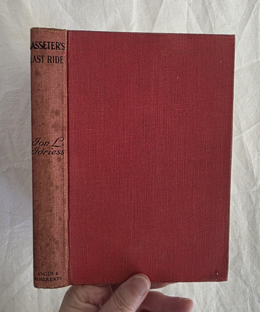 Red book titled 'Asseter's Last Ride' held by a hand on a textured white background