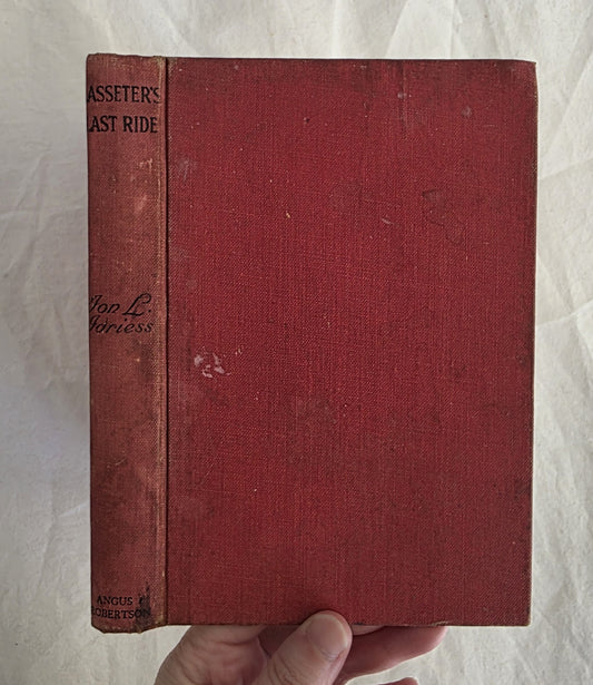 Red book titled 'Lasseter's Last Ride' held by a hand on a textured white background