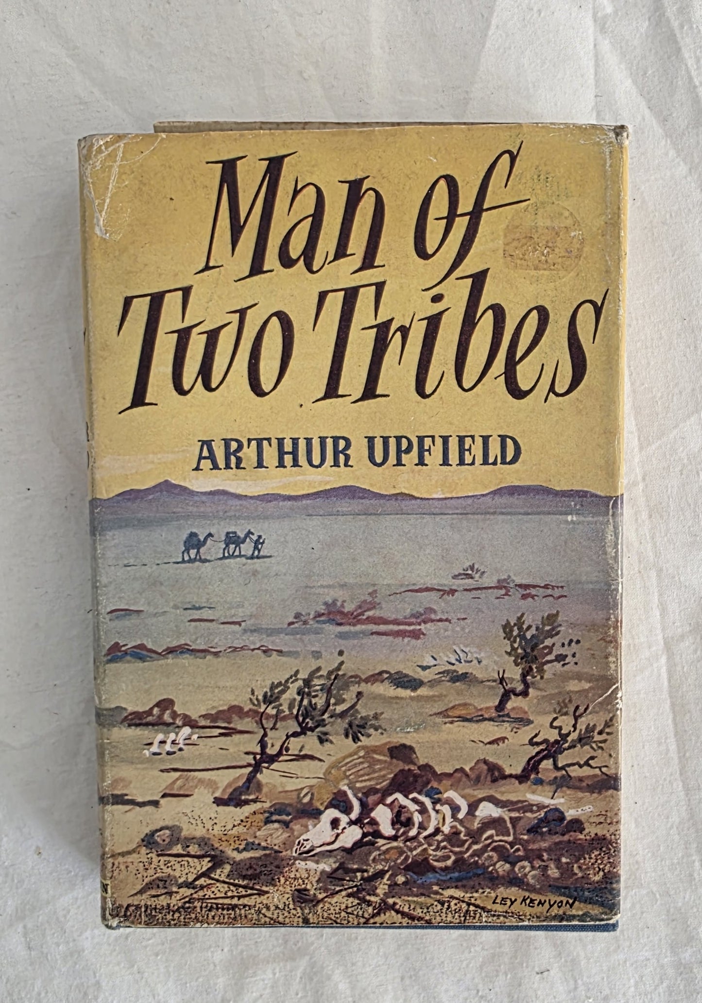 Book cover of 'Man of Two Tribes' by Arthur Upfield with a desert landscape illustration.