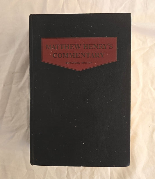 Black book with a red leather patch labeled 'Matthew Henry's Commentary' on a textured beige background
