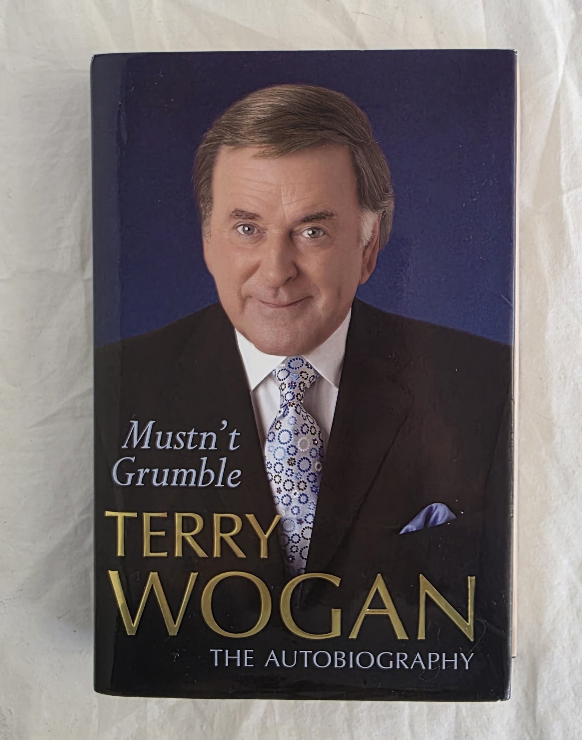 Book cover of 'Mustn't Grumble' by Terry Wogan on a textured white background