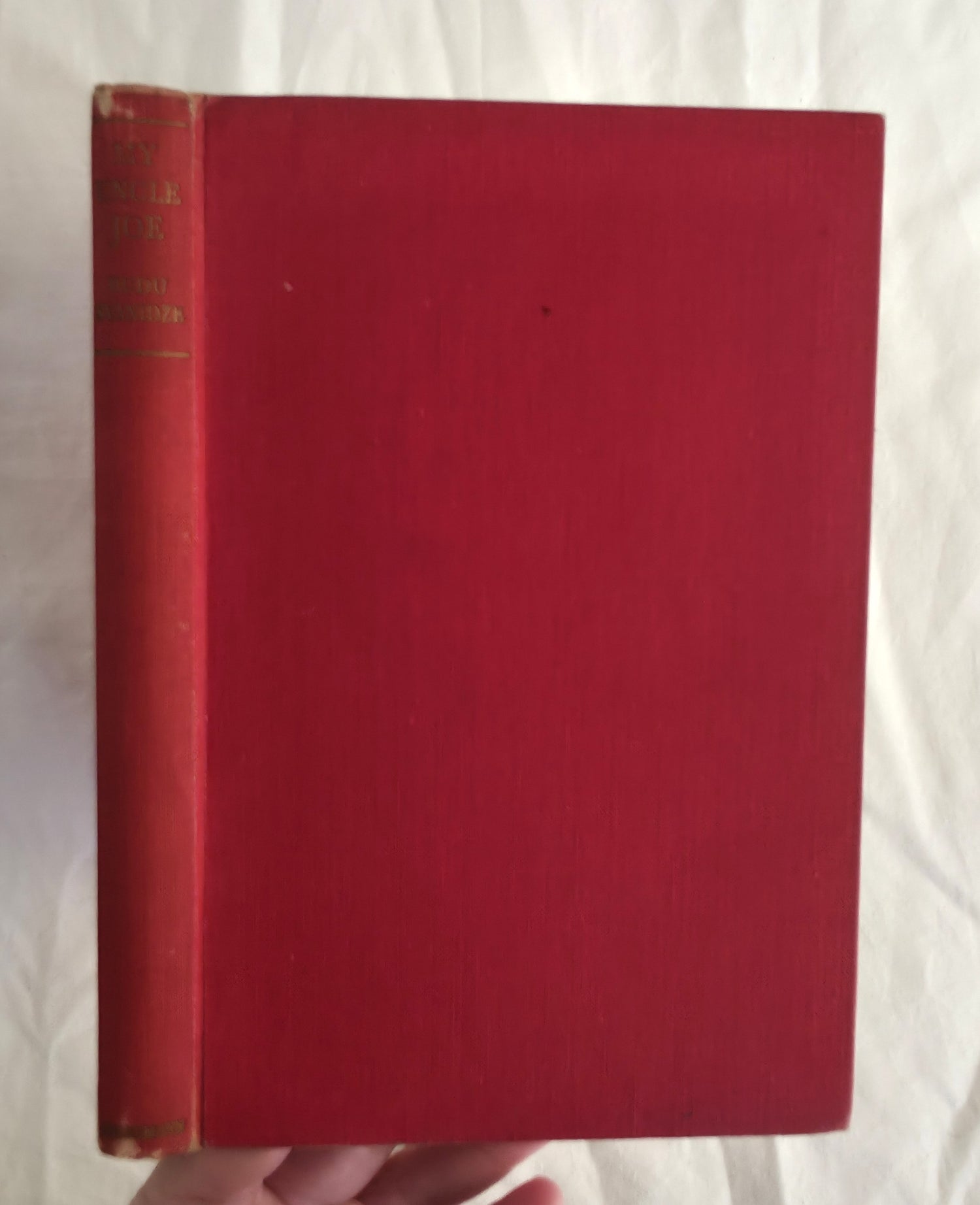 Red book held by a hand against a white background