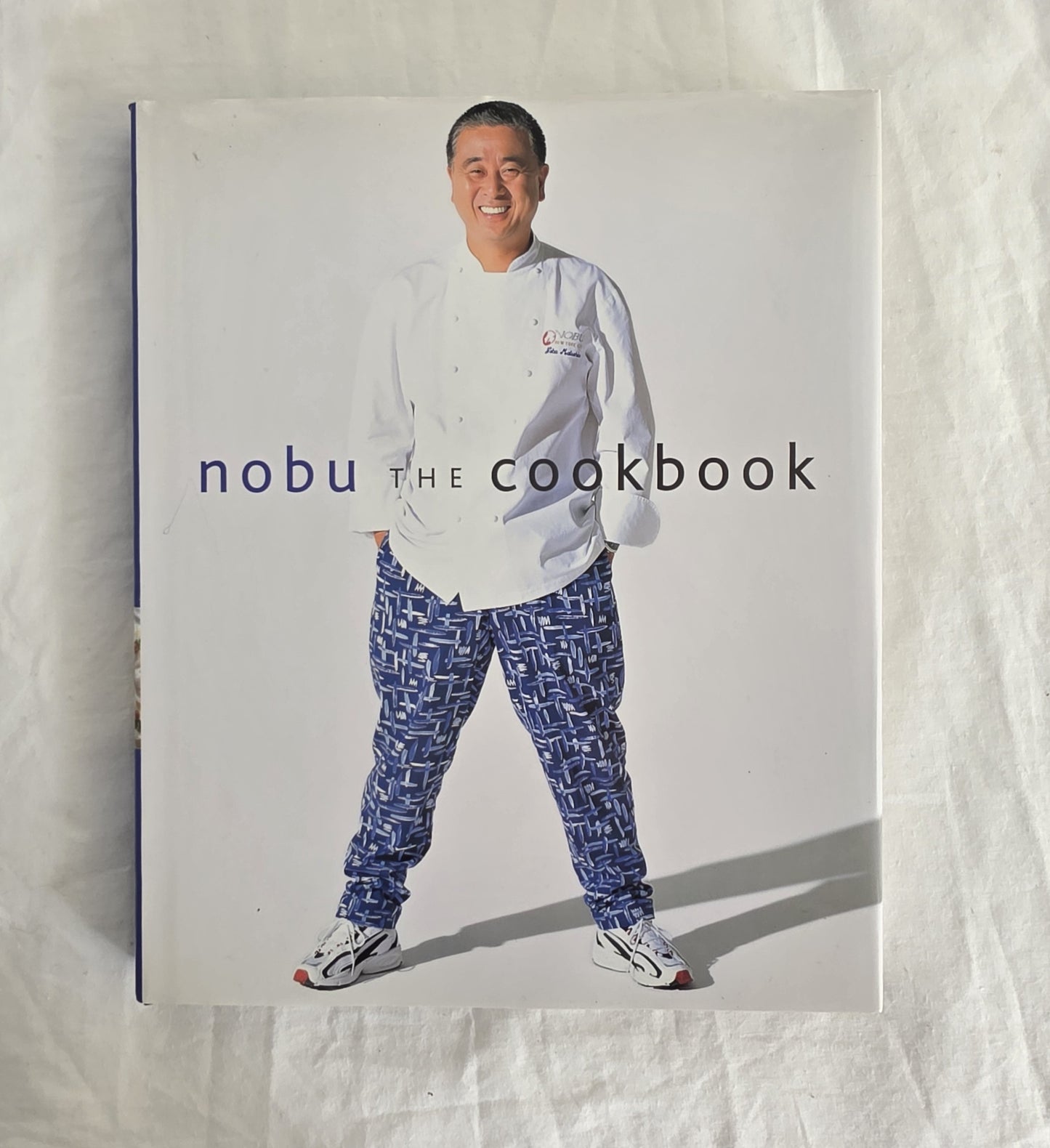 Cookbook titled 'nobu THE COOKBOOK' with a person wearing a chef's outfit on the cover.