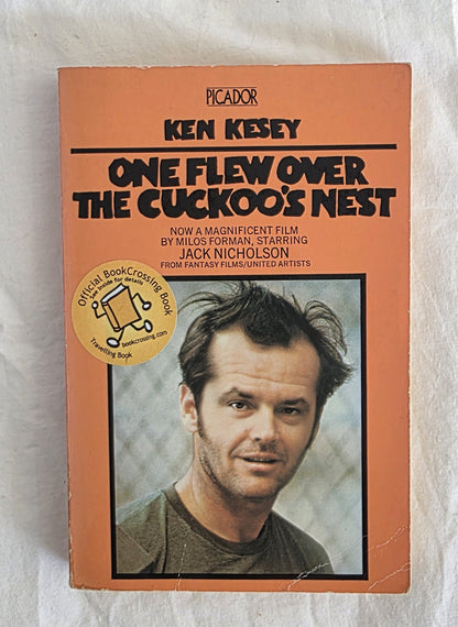 Book cover of 'One Flew Over the Cuckoo's Nest' by Ken Kesey with a photo of Jack Nicholson on an orange background.