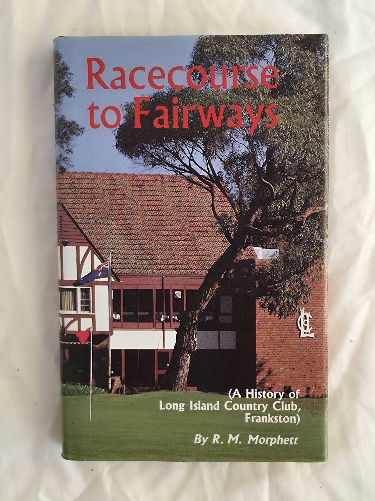 Book cover of 'Racecourse to Fairways' with a building and tree on the cover
