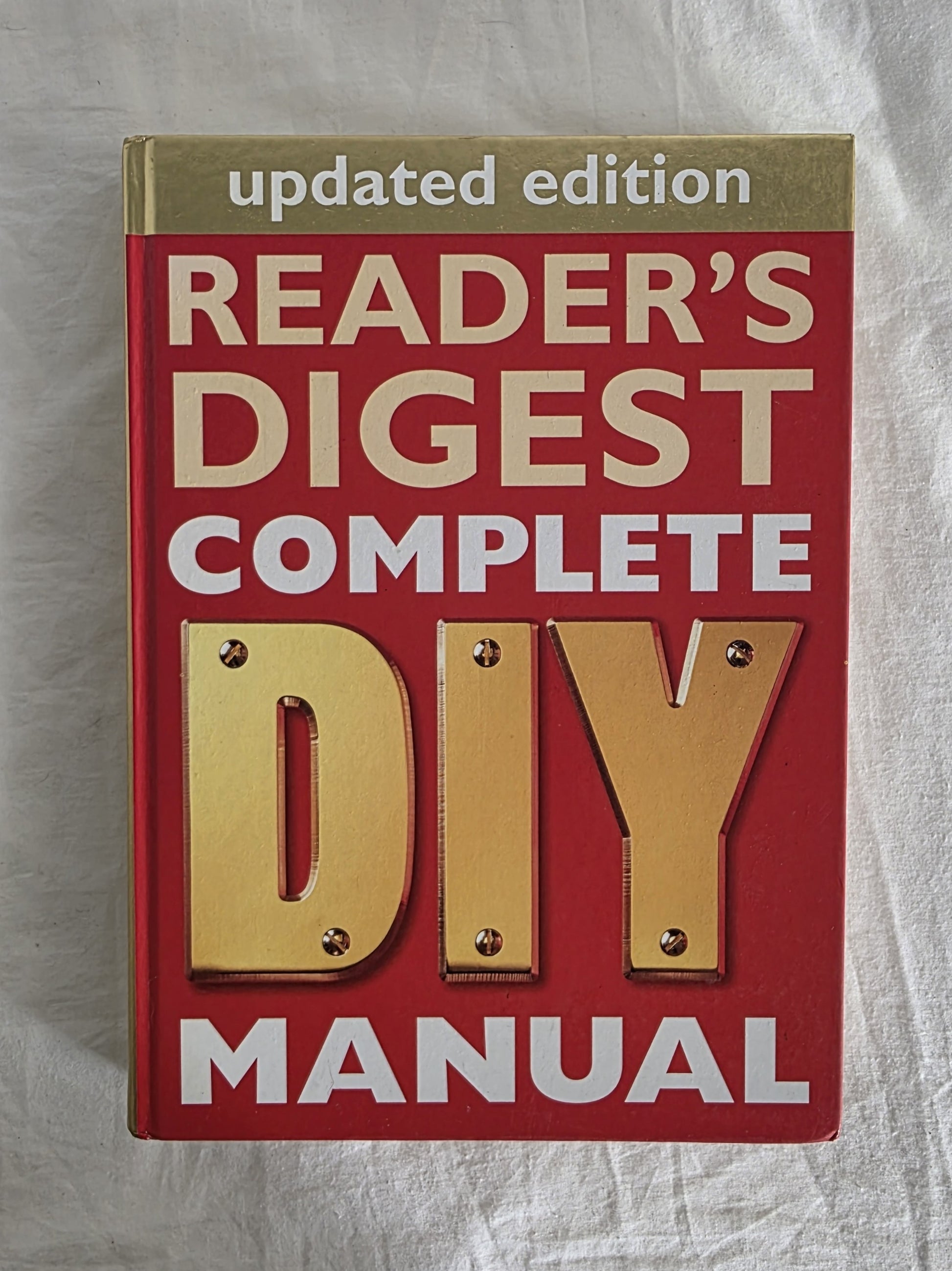 Book titled 'Reader's Digest Complete DIY Manual' on a textured surface