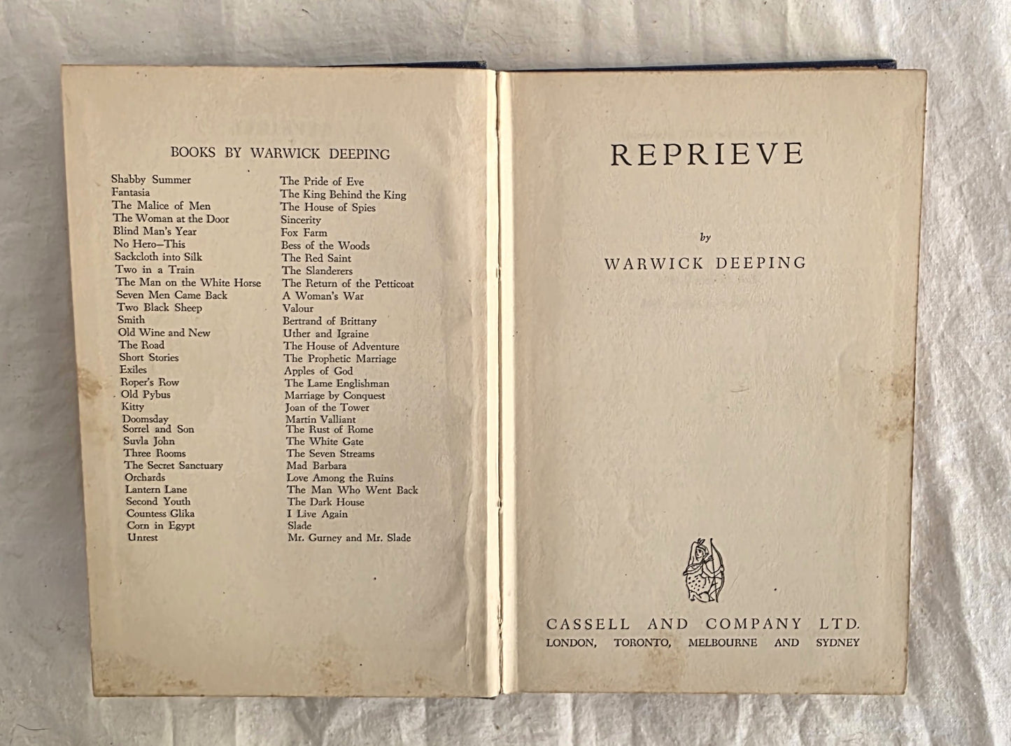 Open book showing the title 'Reprieve' by Warwick Deeping with a list of books on a textured background.