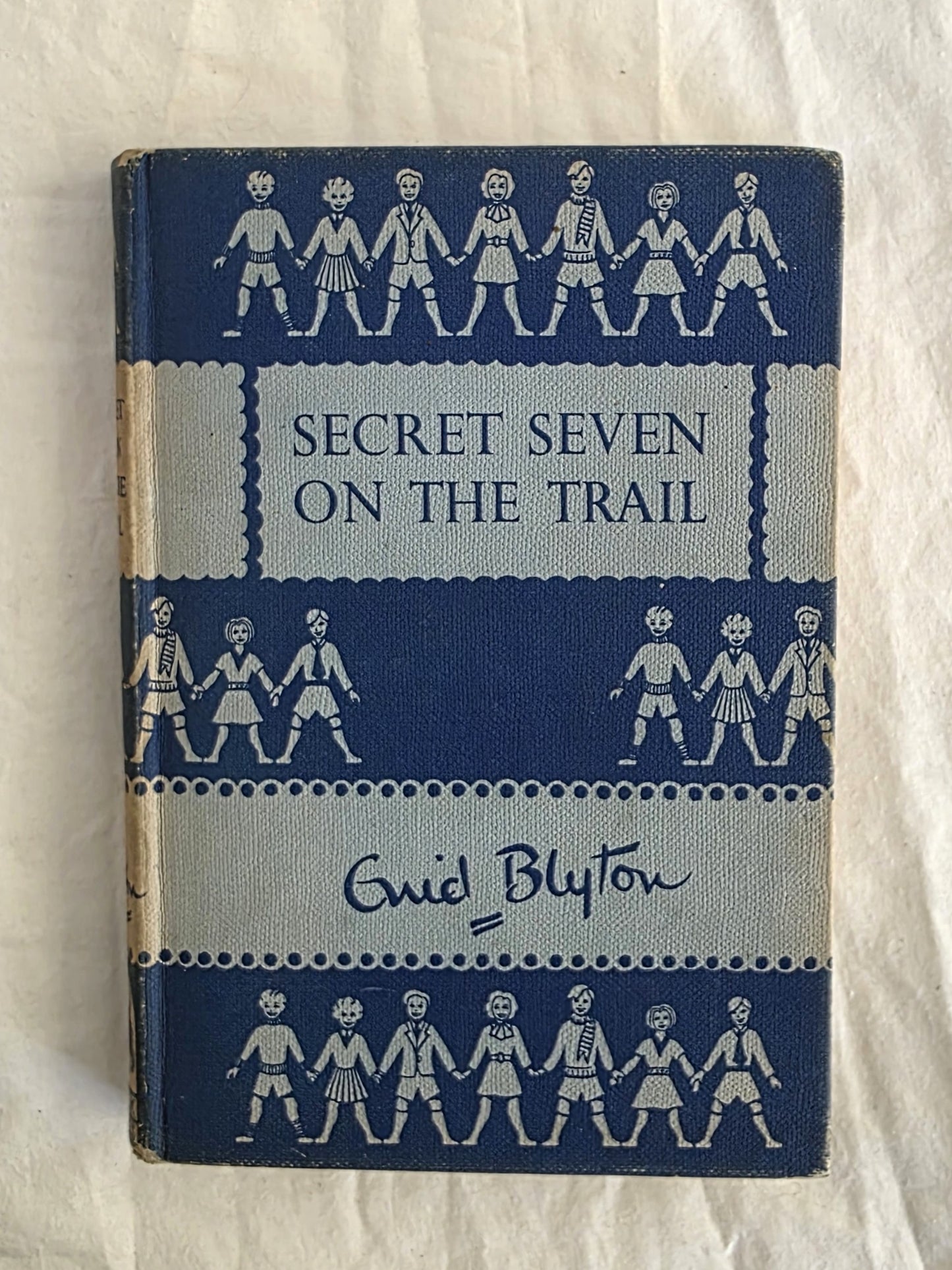 Book titled 'Secret Seven on the Trail' by Enid Blyton with blue and white cover design.
