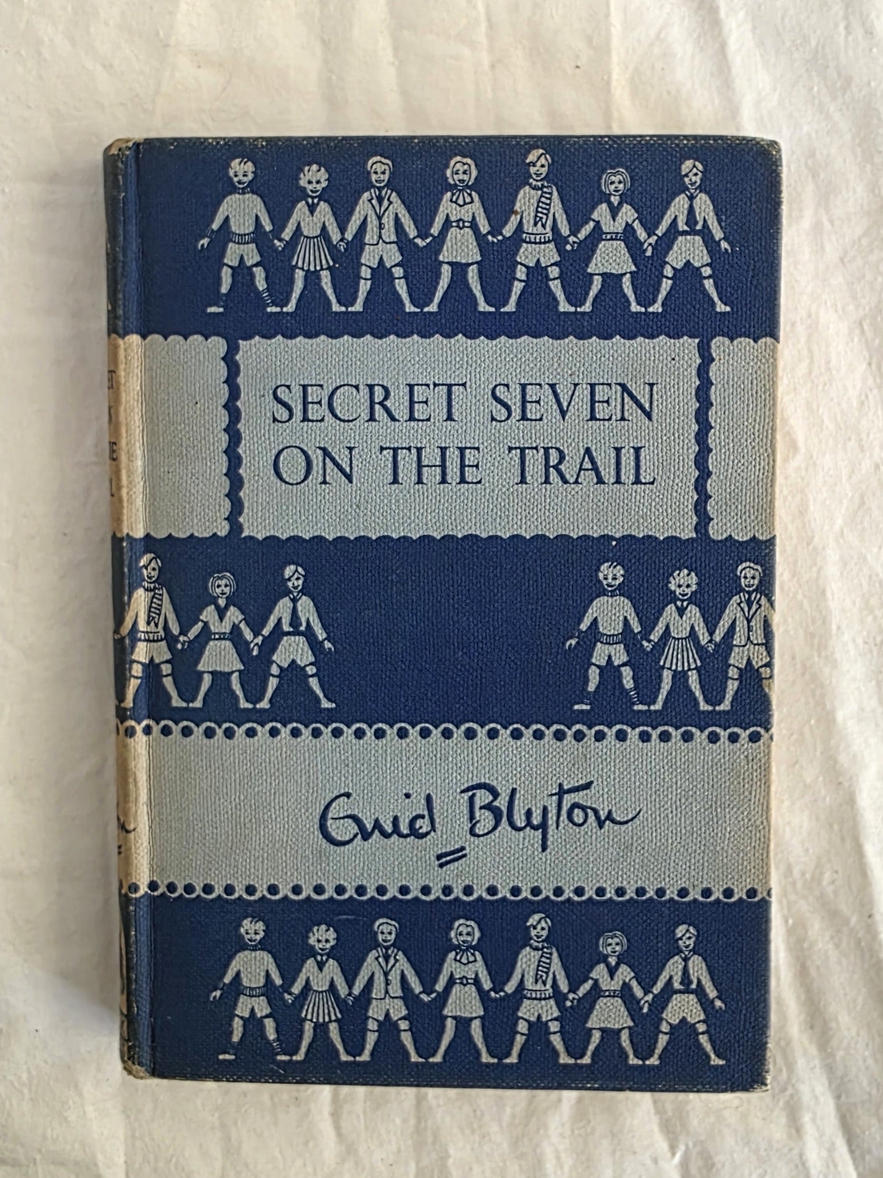 Book titled 'Secret Seven on the Trail' by Enid Blyton with blue and white cover design.