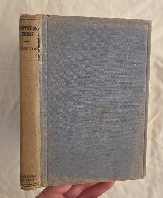 Vintage book with a blue cover and brown spine held by a hand on a light background