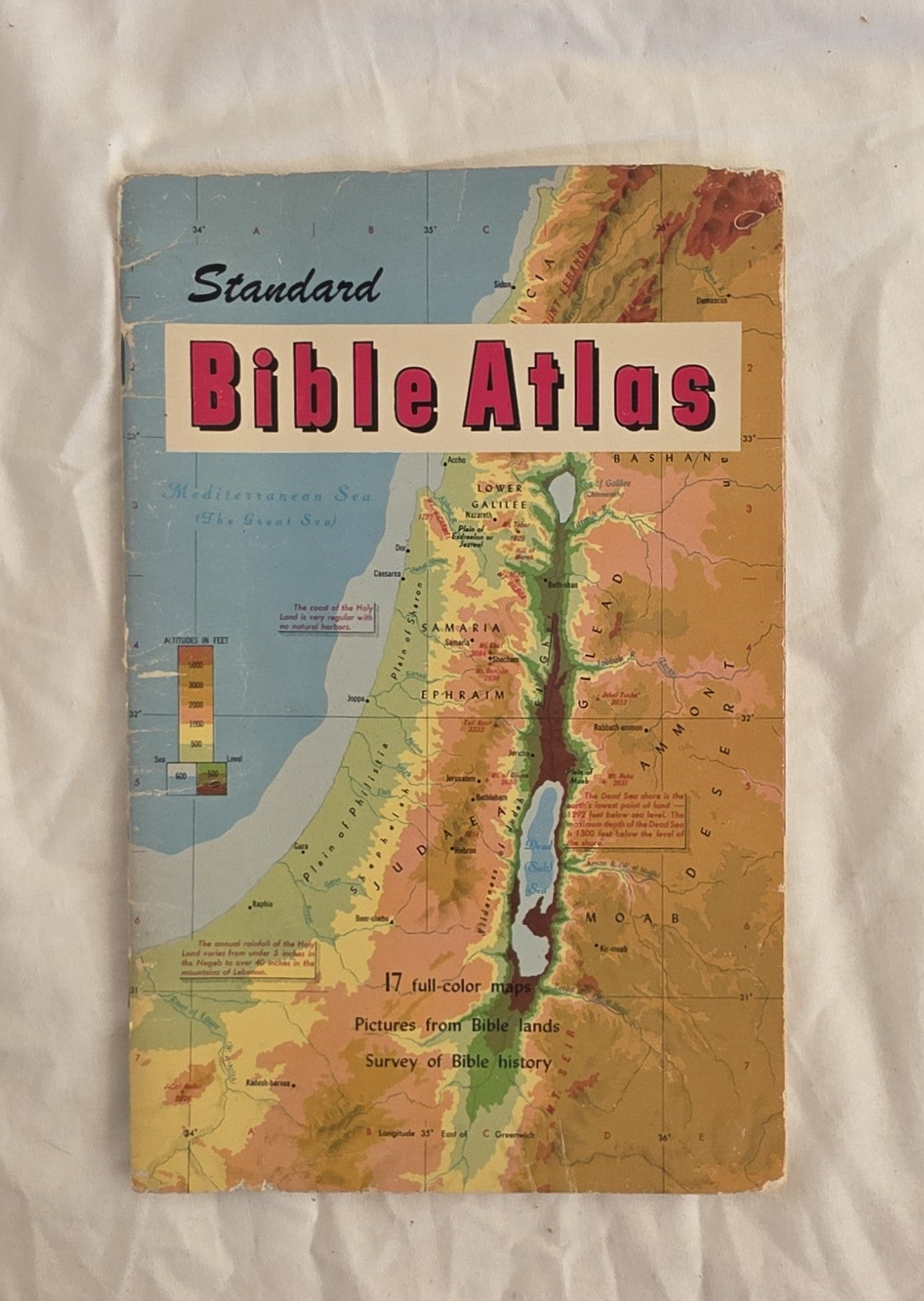 Vintage 'Standard Bible Atlas' book cover with map illustrations on a textured surface