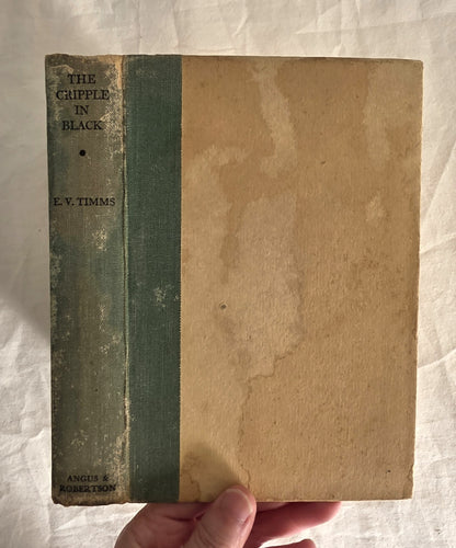 Vintage book titled 'The Cripple in Black' by E.V. Timms held against a textured white background.