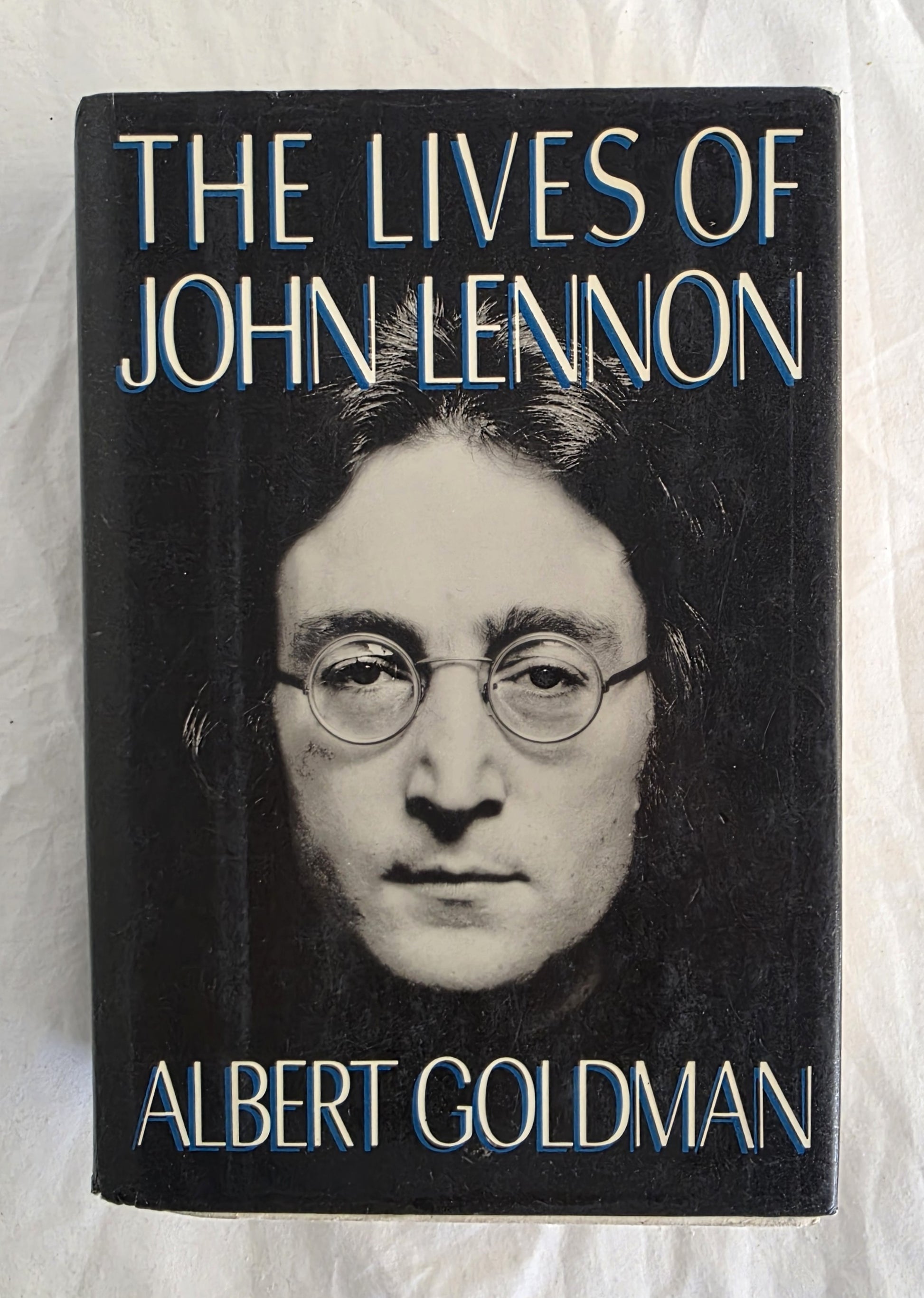 Book cover of 'The Lives of John Lennon' by Albert Goldman on a textured white background