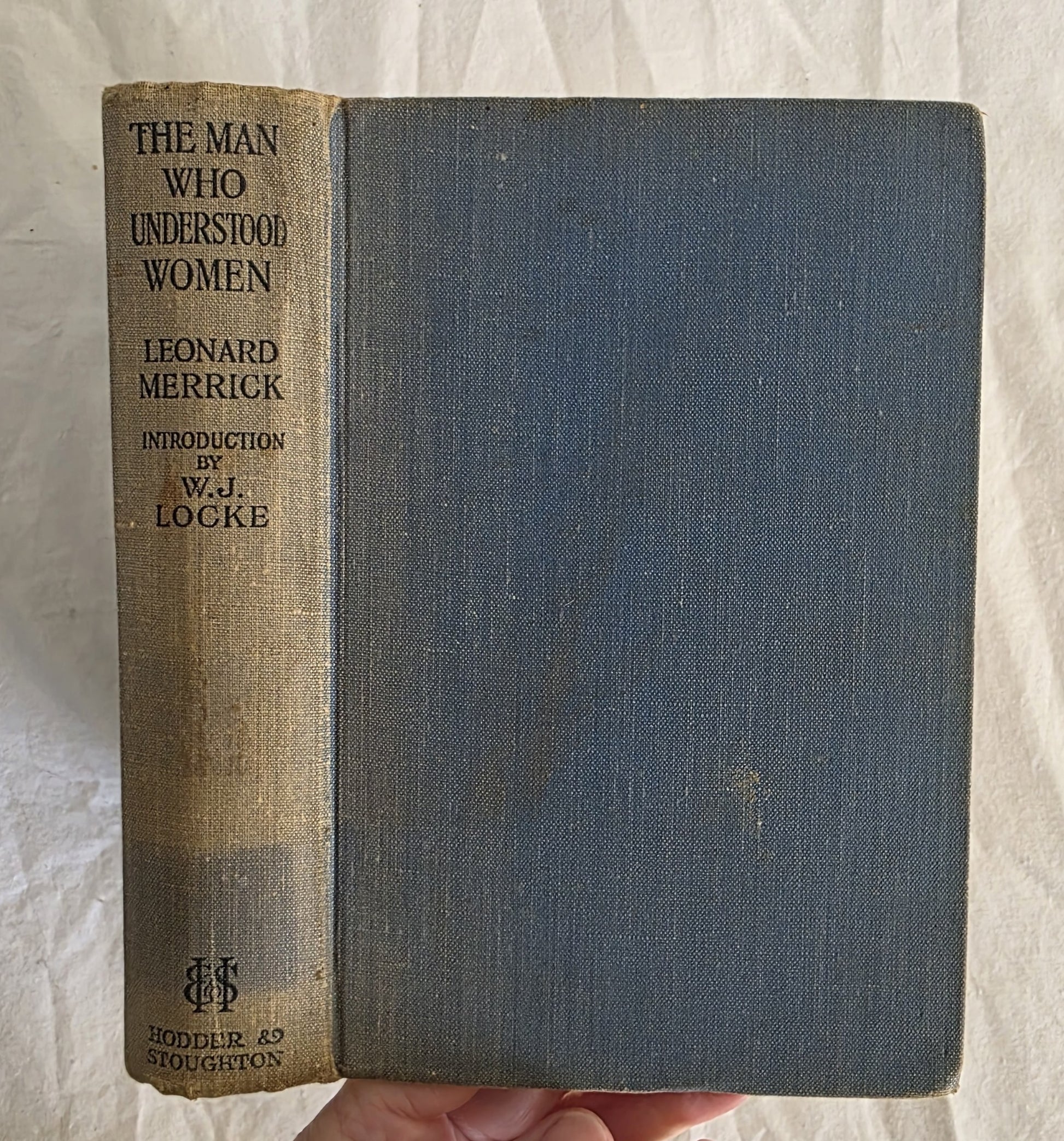Vintage book titled 'The Man Who Understood Women' by Leonard Merrick, held against a textured white background.