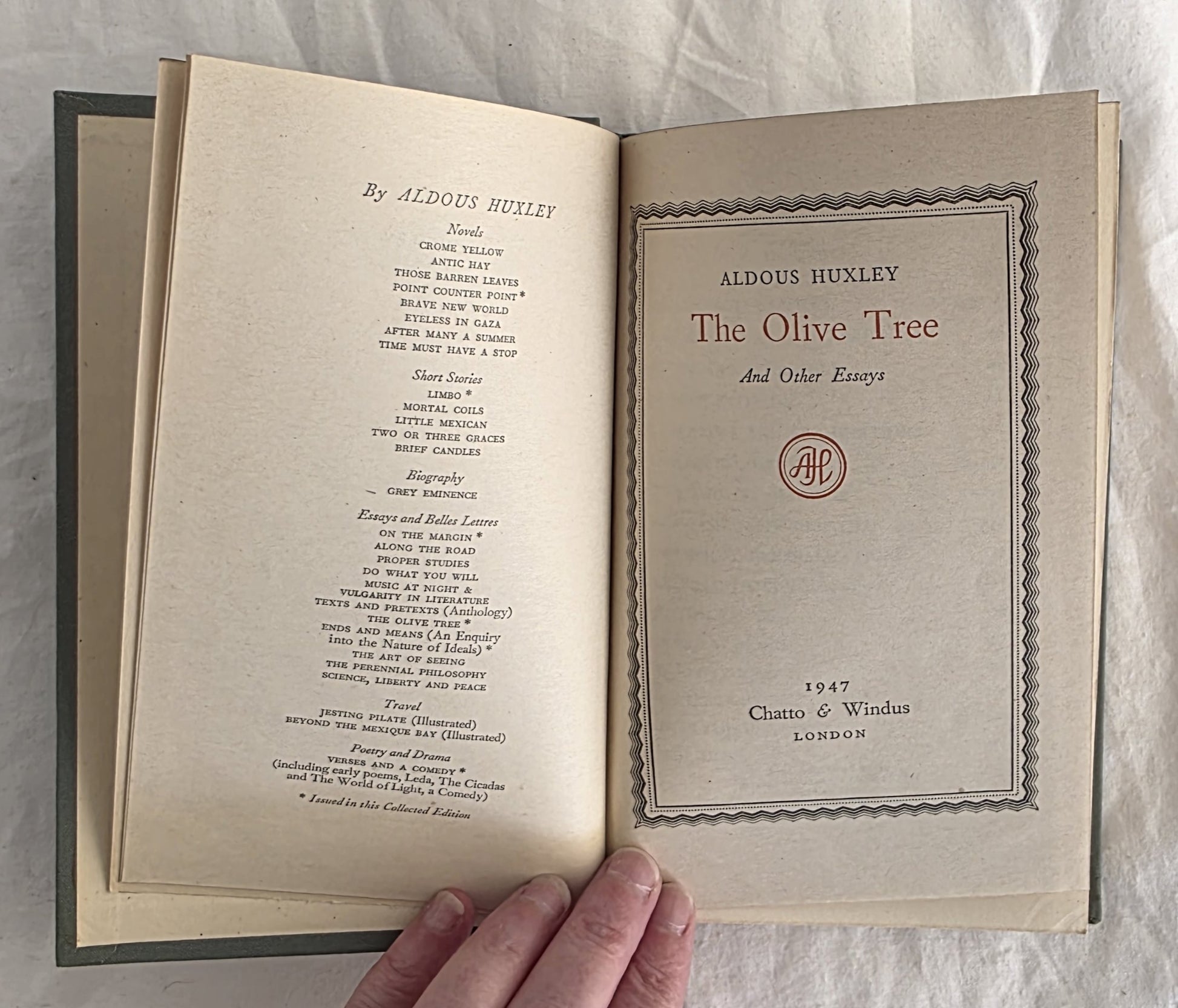 Open book titled 'The Olive Tree' by Aldous Huxley on a textured surface