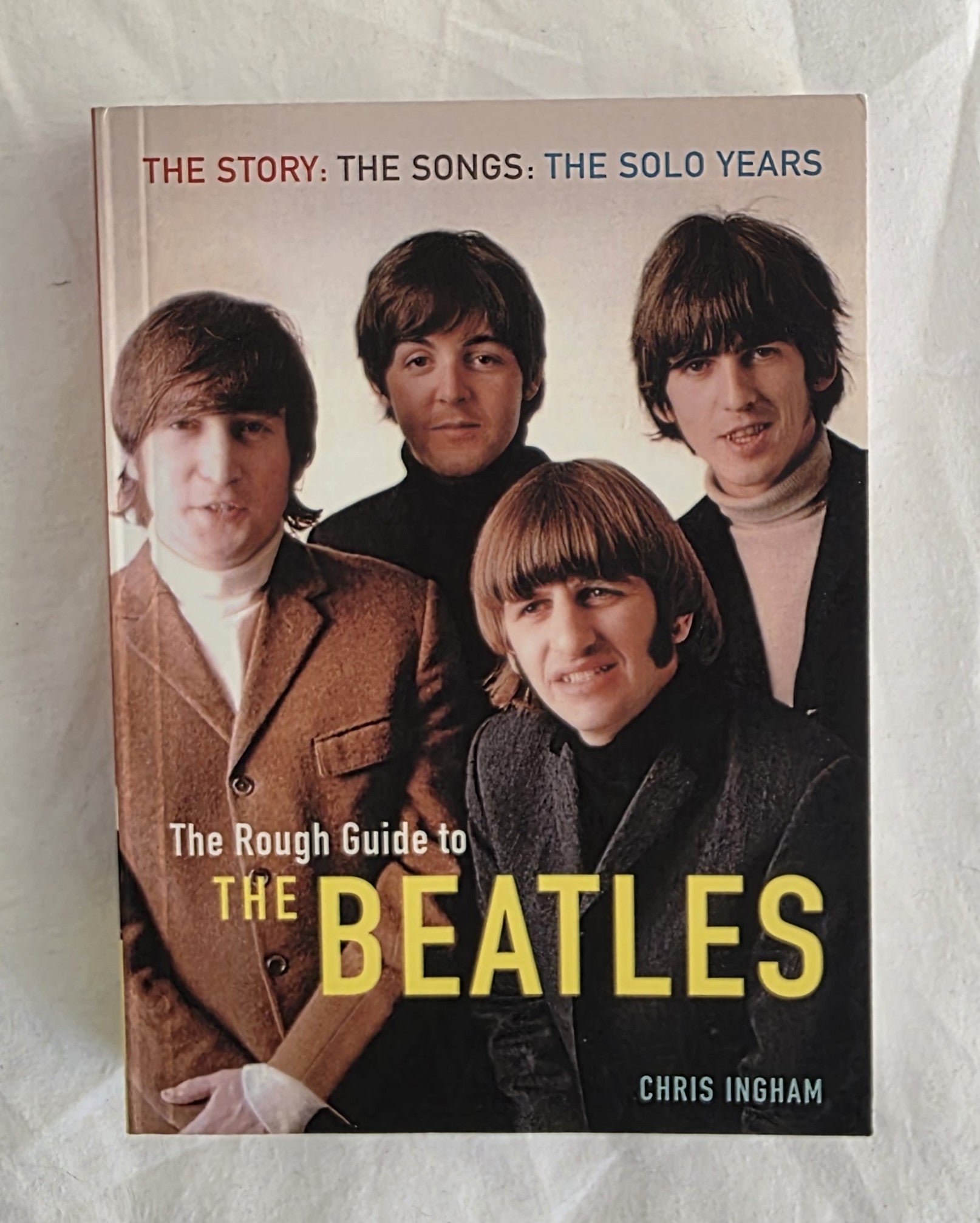 Book cover of 'The Rough Guide to The Beatles' featuring four band members on a white background