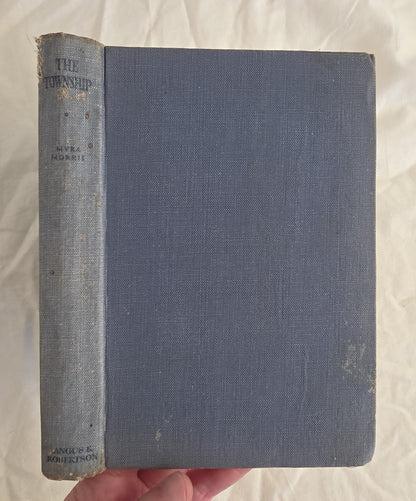 Vintage book titled 'The Township' held by a hand on a textured white background